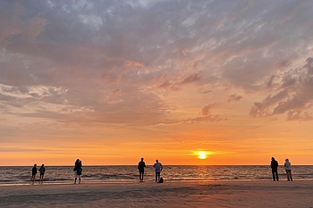 Menschen beobachten den orange leuchtenden Sonnenuntergang