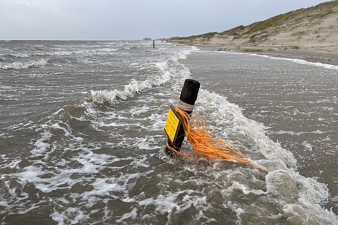 Pfahl und Absperrband in hohen Wellen