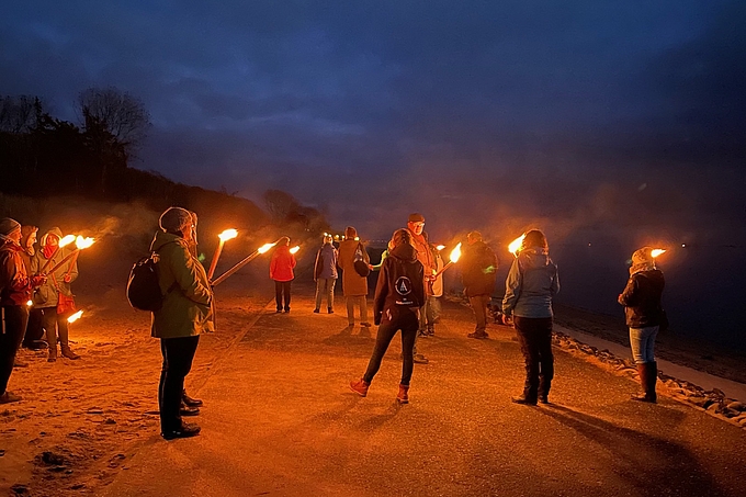 Gruppe mit Fackeln am Strand