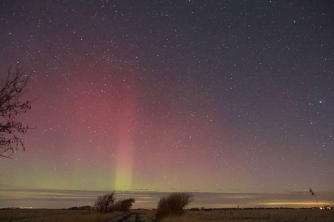 Starker Lichtstrahl reicht hoch bis in roten Schimmer