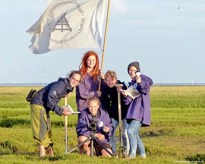 Freiwilligen-Team Schutzstation Wattenmeer mit Flagge und Arbeitsgeräten