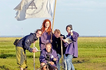 Freiwilligen-Team Schutzstation Wattenmeer mit Flagge und Arbeitsgeräten