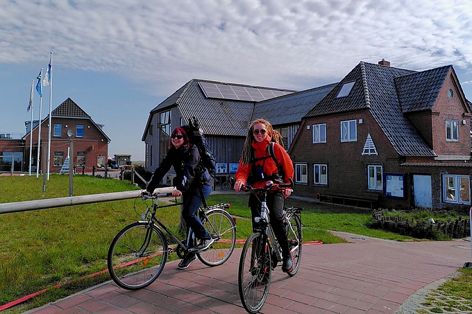 Zwei Radfahrerinnen mit Rucksäcken vor der Station