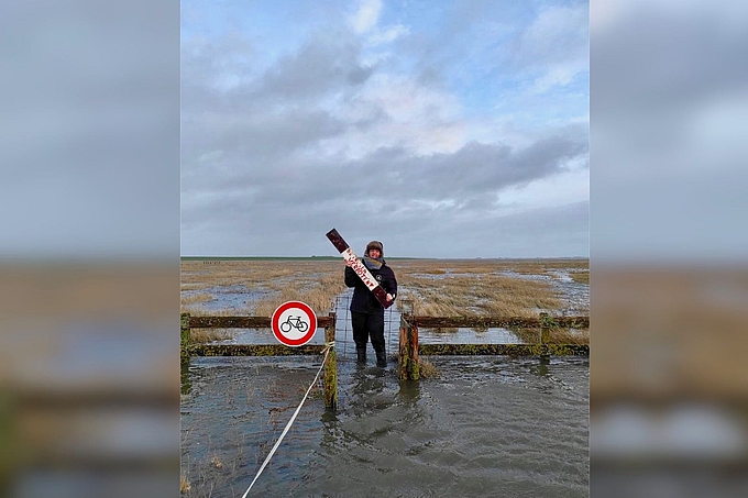 Freiwillige Tabea im steigenden Wasser mit Schild in der Hand