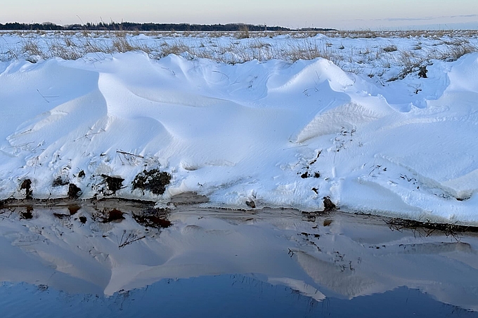 Schneeverwehungen spiegeln sich in Wasser
