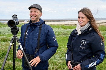Zwei Personen mit Fernrohr auf der Hallig