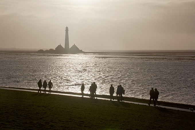 Wanderer am Deich vor dem Leuchtturm Westerhever