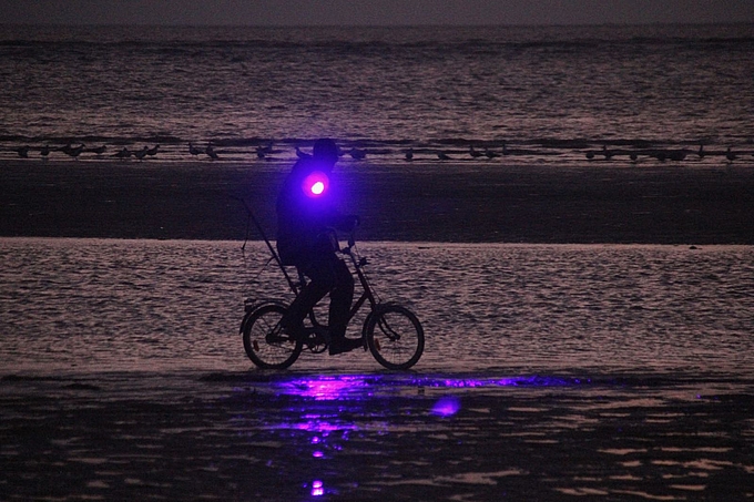 Am Wasser radelnder Bernsteinsucher mit UV-Scheinwerfer