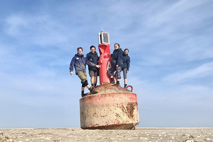 Team auf angetriebener Tonne auf dem Blauortsand