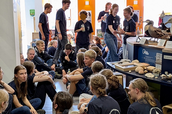Freiwillige sitzen und stehen dicht gedrängt
