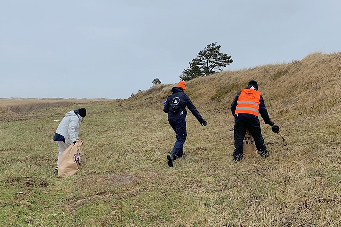 Drei sammelnde Menschen in den Dünen