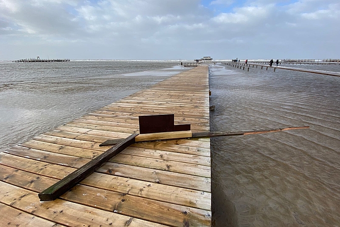 Holzteile auf einem Steg auf der überfluteten Sandbank