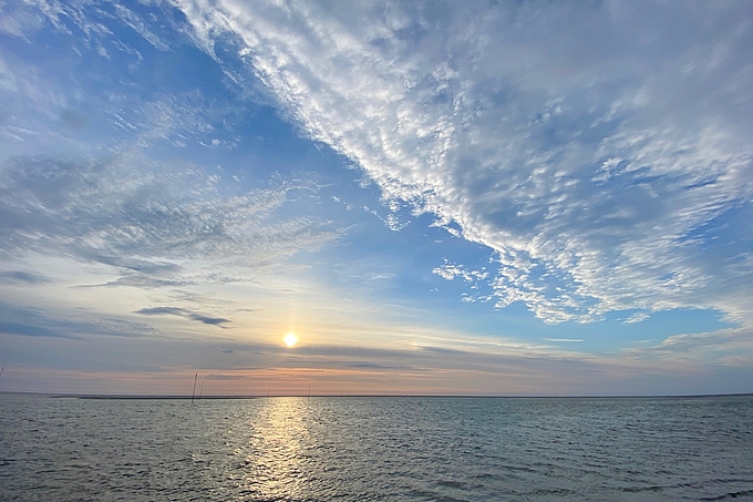 Lockere Wolken vor tief stehender Sonne