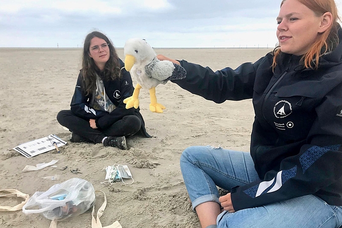 Freiwillige mit Müllteilen im Sand