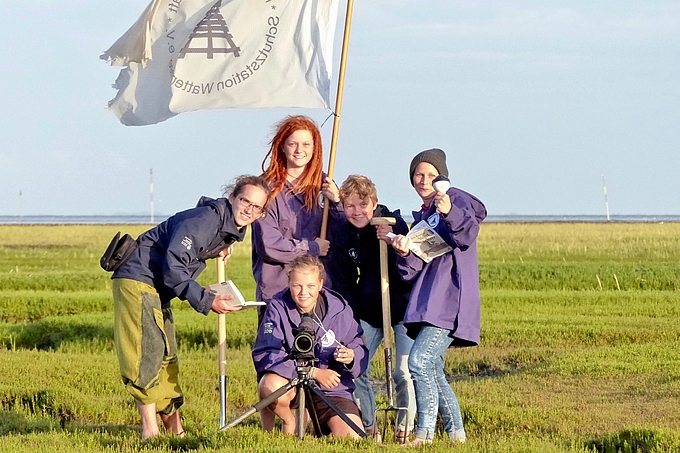 Freiwillige mit Arbeitsgeräten und Flagge