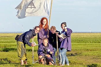 Freiwilligen-Team mit Flagge und Arbeitsgeräten