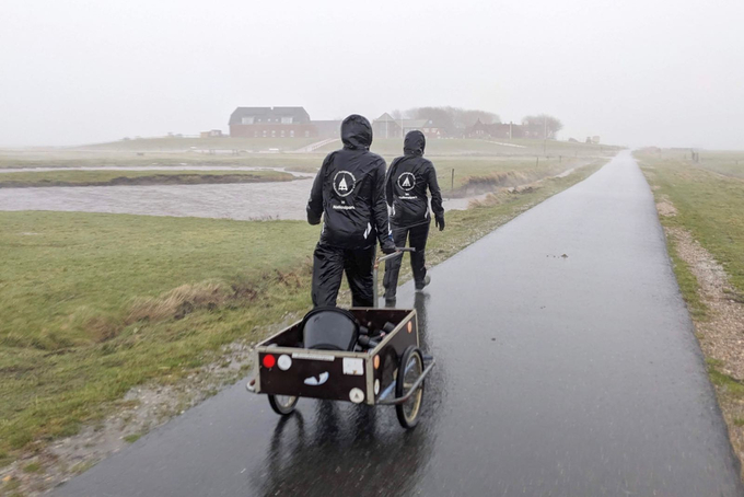 Zwei Freiwillige mit Handwagen im Regen