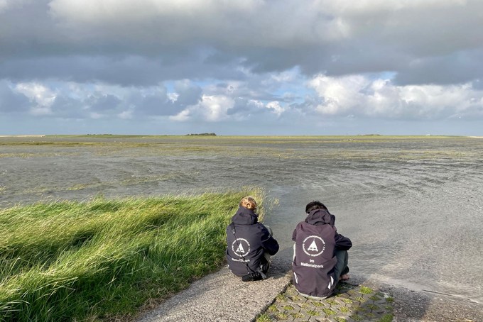 Zwei Freiwillige blicken auf überflutete Salzwiesen