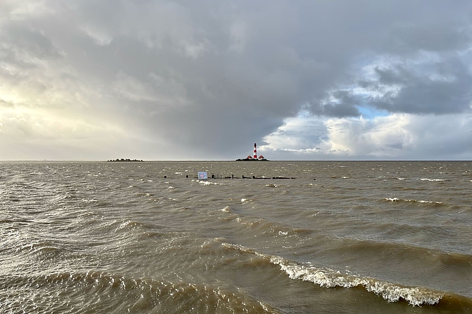Überflutete Salzwiese mit Leuchtturm im Hintergrund