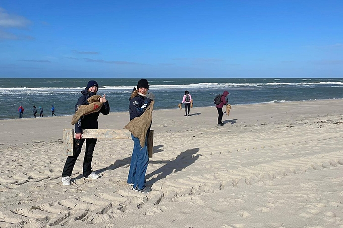 Freiwillige und Gäste mit Müllsäcken am Strand