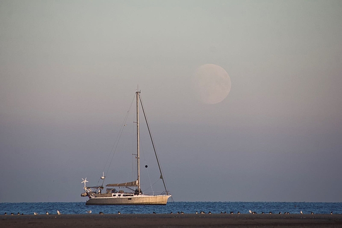 Mond geht hinter Segelboot auf