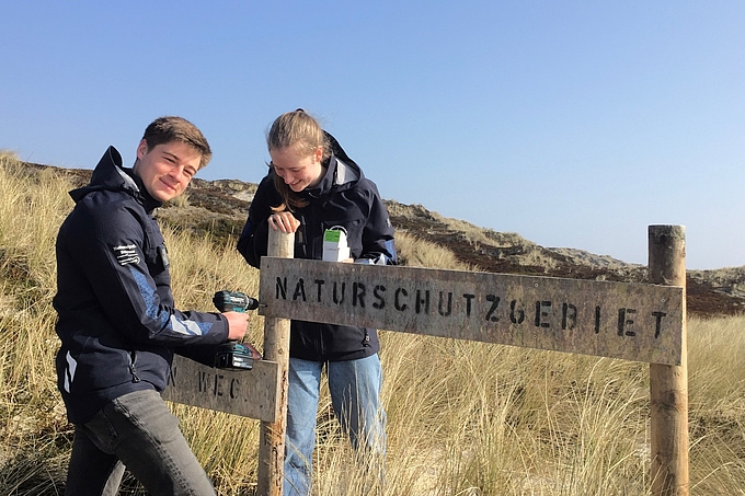 Zwei Freiwilligen befestigen Schild