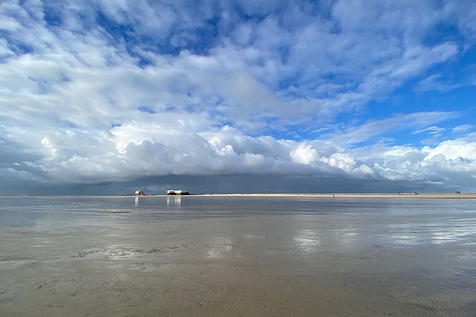 Sandbank und Pfahlbauten unter Wolkenhimmel