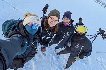 Team in Winterkleidung mit Fernrohren