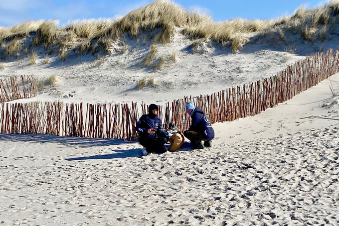 Zwei Freiwillige knien im Sand