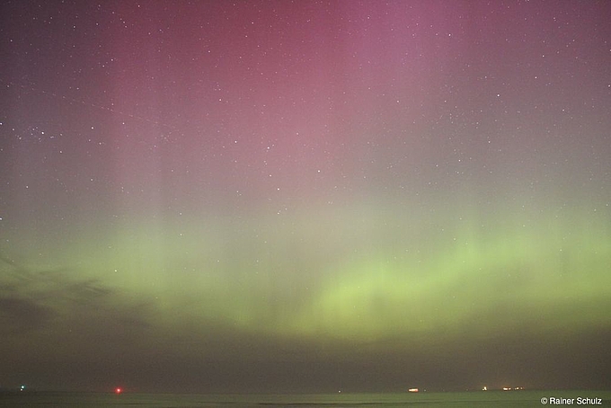 Leuchtend grüner und roter Himmel über der See