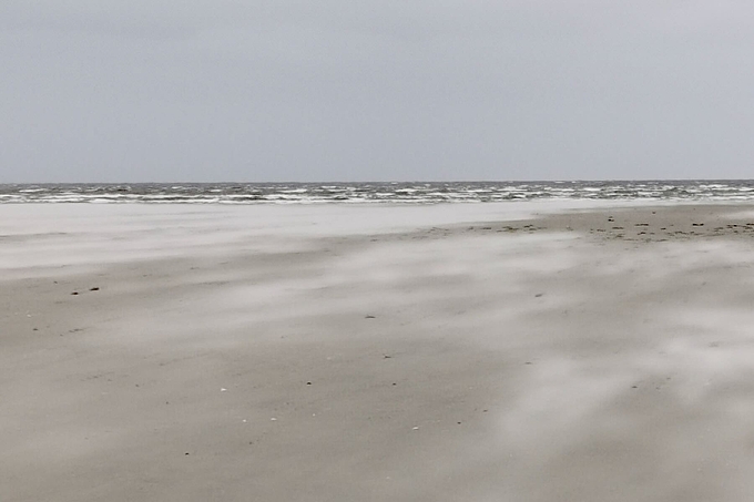 Sandflug und Wellen