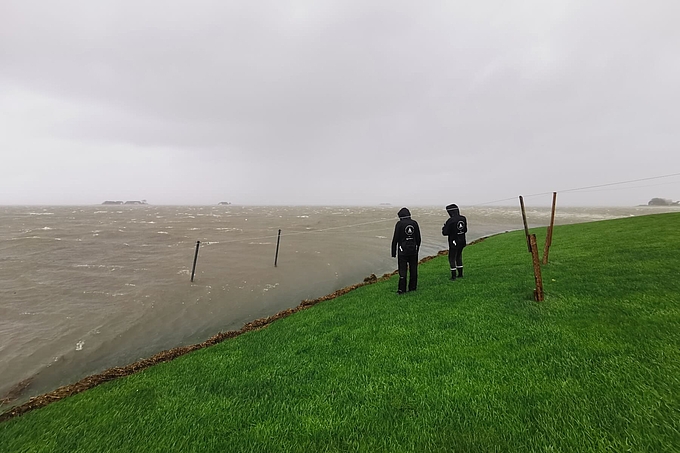 Zwei Personen blicken auf das Landunter Zwei Personen blicken auf das Landunter