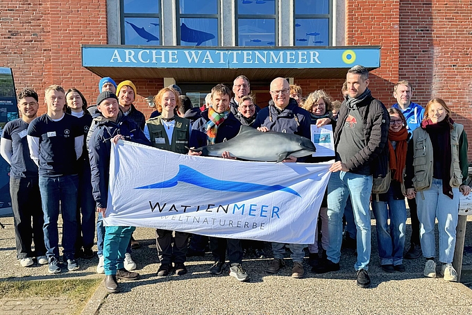 Gruppenbild mit Schweinswal und Welterbe-Flagge
