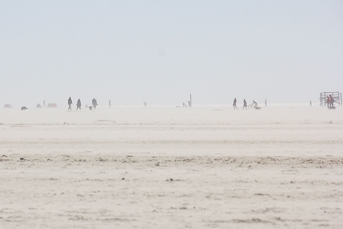 Personen und Hund in fliegendem Sand