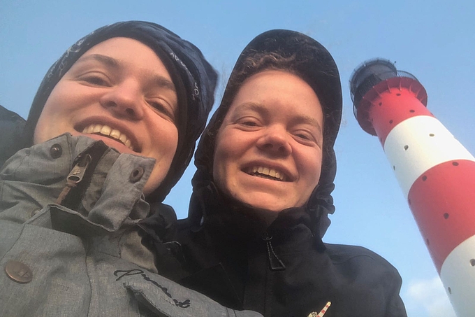 Freiwillige blicken vor dem Leuchtturm in die Kamera