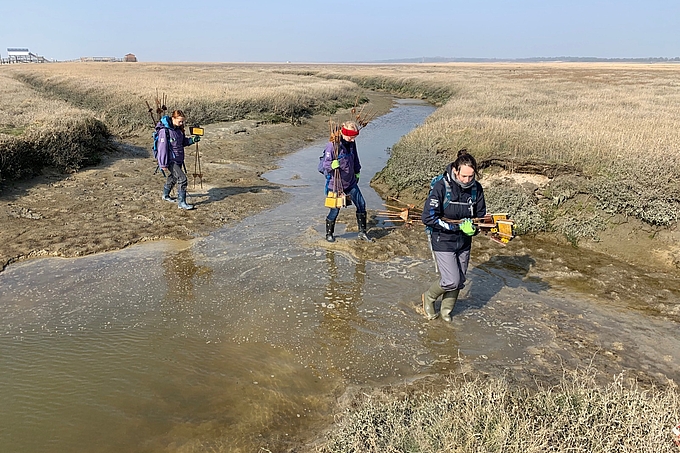 Schilder tragende Freiwilllige durchqueren einen Wasserlauf