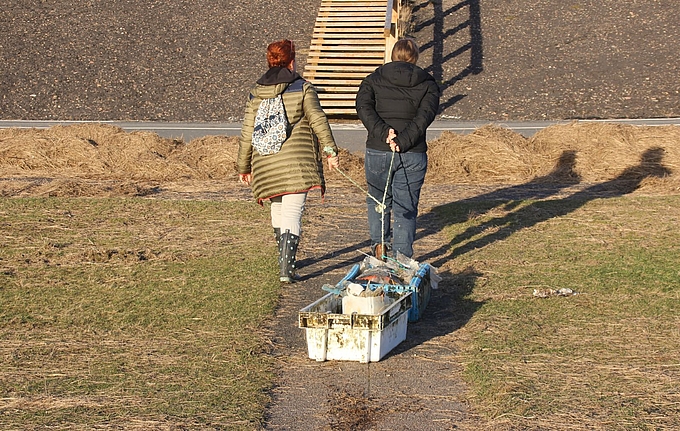 Zwei Frauen ziehen Müll zum Deich