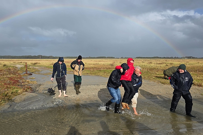 Person in Schuhen wird über Priel getragen Person in Schuhen wird über Priel getragen