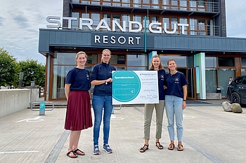 Gruppenbild mit Scheck vor dem Hotel