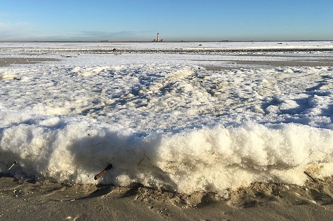 Eisschollen auf dem Watt unter blauem Himmel