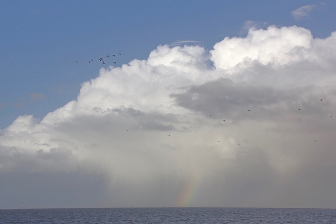 Weiße Wolkenberge mit kurzem Regenbogen