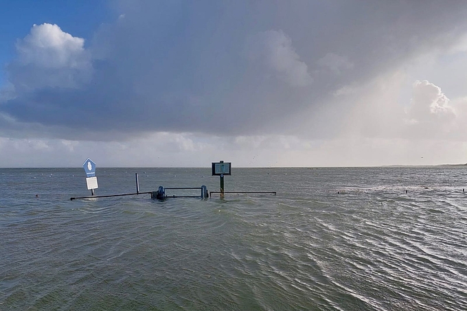 Zaun und Schilder ragen aus dem Wasser