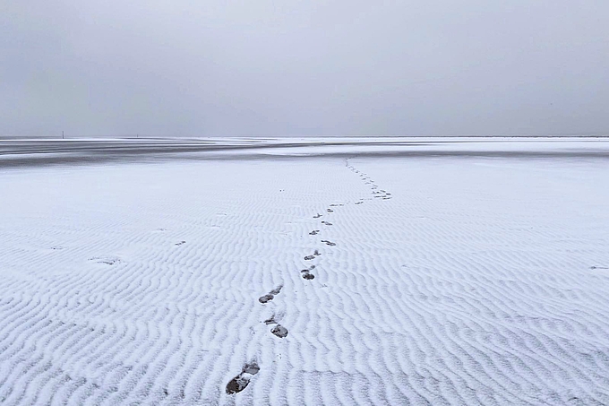 Fußspur im verschneiten Watt